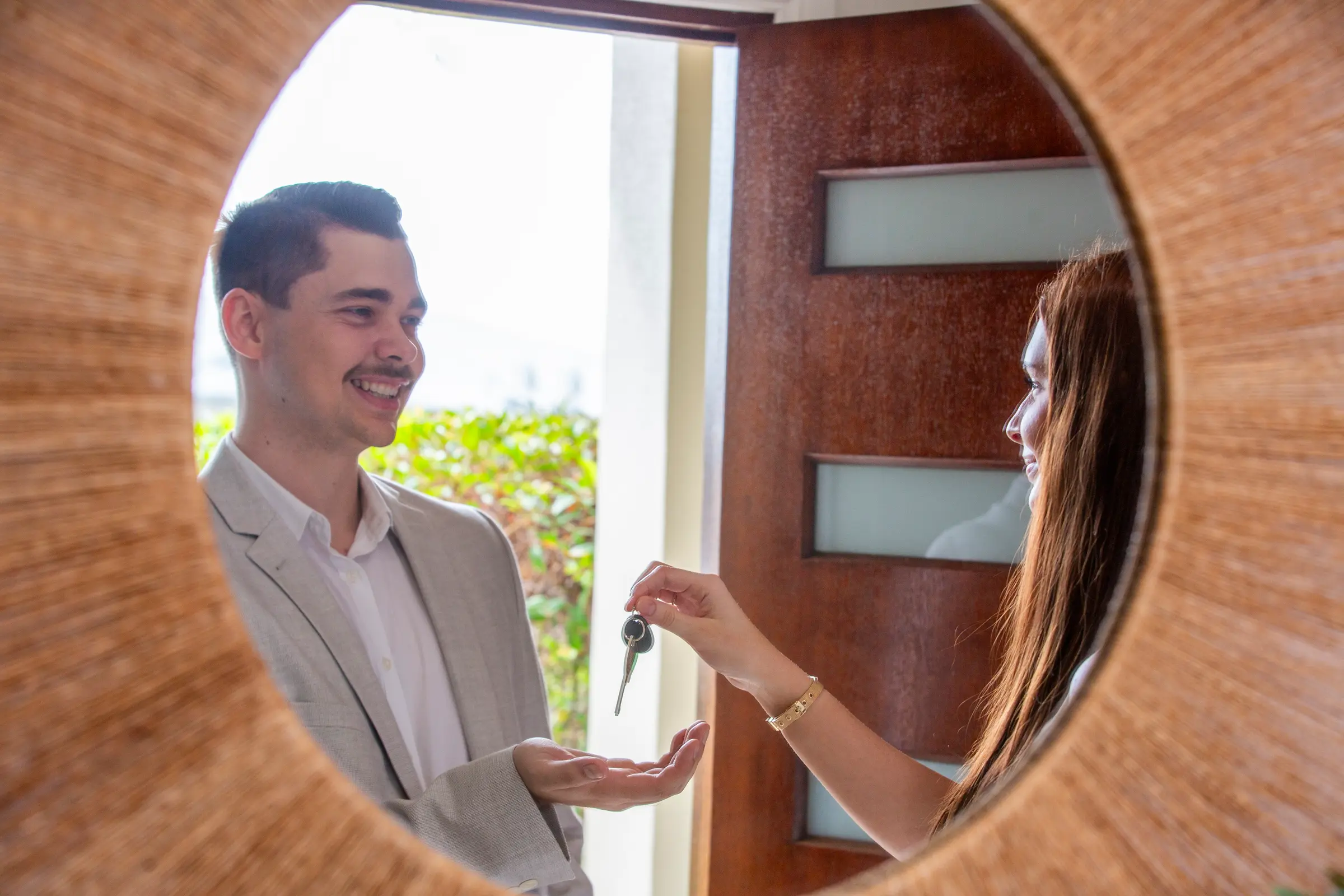 Keys changing hands at the front door of a Smart Rentals managed home, seen in a round mirror